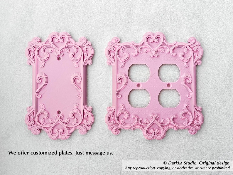 Puede incluir: Dos placas decorativas rosas para interruptores de luz con adornos de volutas y detalles en forma de coraz&oacute;n. Una es una placa de un solo interruptor y la otra tiene cuatro orificios para enchufes. El texto dice: "Ofrecemos placas personalizadas. Cont&aacute;ctenos."