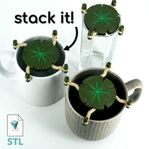 May include: Three green and brown leaf-shaped coasters with a star design in the centre. The coasters are stacked on top of each other. The text "stack it!" is written in black on a white background.
