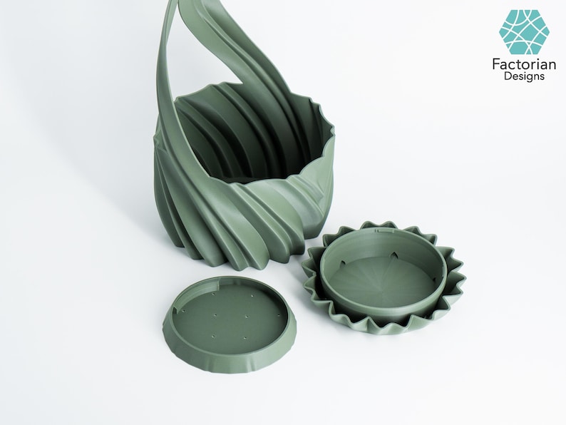 K&ouml;nnte beinhalten: Ein salbeigr&uuml;ner, 3D-gedruckter Pflanztopf mit einem einzigartigen, wirbelnden Design und einem Griff. Der Pflanztopf wird von zwei passenden gr&uuml;nen, kreisf&ouml;rmigen Teilen begleitet, wahrscheinlich einem Boden und einem Deckel. Das Logo von Factorian Designs befindet sich oben rechts.