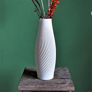 Puede incluir: Jarr&oacute;n de cer&aacute;mica blanco con un dise&ntilde;o de textura en espiral. El jarr&oacute;n est&aacute; vac&iacute;o y se encuentra sobre una mesa de madera.