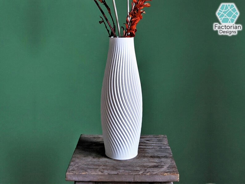 Puede incluir: Jarr&oacute;n de cer&aacute;mica blanco con un dise&ntilde;o de textura en espiral. El jarr&oacute;n est&aacute; vac&iacute;o y se encuentra sobre una mesa de madera.