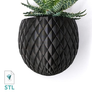 Puede incluir: Un macetero geométrico negro con un patrón de diamantes. El macetero está vacío y listo para ser llenado con plantas.