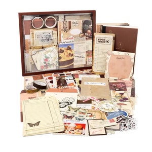 May include: A collection of vintage-style paper ephemera, including stickers, washi tape, and decorative paper. The items are arranged in a brown wooden box and on a white background. The paper features floral patterns, butterflies, and other whimsical designs.