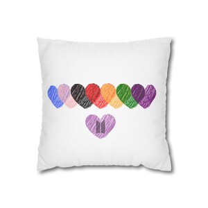 May include: White pillow with a colorful rainbow of hearts and a purple heart with the letters "BT" in the center.