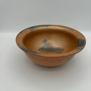 以下が含まれることがあります： 黒い斑点と黒い縁のある、小さく丸いオレンジ色のセラミックボウル