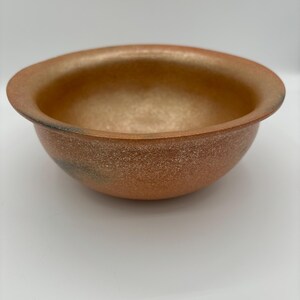 以下が含まれることがあります： 斑点のある薄い茶色の釉薬が施された、小さな丸いテラコッタ製のボウル。ボウルはわずかに広がった縁と滑らかで光沢のある内側を持っています。