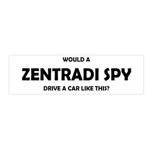 May include: A white rectangular sign with black text that reads "Would a Zentradi Spy drive a car like this?"
