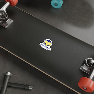 Könnte beinhalten: Ein schwarzes Skateboard mit einem gelben und blauen Wu-Tang Clan Logo-Aufkleber, auf dem "Star Max Print Co." steht.