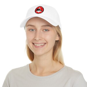 May include: White baseball cap with a red and black logo featuring a star and a plane. The logo says "United States Air Force" and "Air Combat Command".