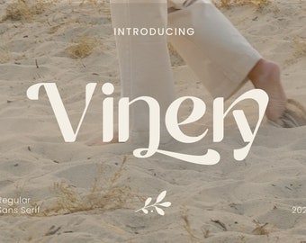 Op de afbeelding: Introductie van Vinery, een regulier sans-serif lettertype. Het lettertype wordt weergegeven in wit tegen een zandige achtergrond met een voet die op het zand loopt.