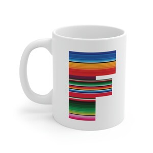 Può includere: Tazza in ceramica bianca con una grande lettera "F" in un motivo a righe colorate. Il design presenta strisce orizzontali nelle tonalità di rosso, arancione, giallo, verde e blu. La tazza ha un manico curvo e una finitura lucida.