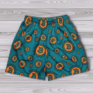 May include: Teal blue athletic shorts with a repeating pattern of orange Bitcoin symbols.