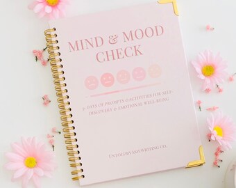 May include: Pink spiral bound journal with the title "Mind & Mood Check" and the text "31 Days of Prompts & Activities for Self-Discovery & Emotional Well-Being" and "Untoldbyash Writing Co."
