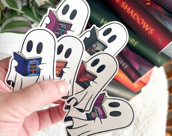 May include: Five white ghost stickers with black eyes, each holding a different book. The books are from the Throne of Glass series by Sarah J. Maas. The stickers are on a stack of books.