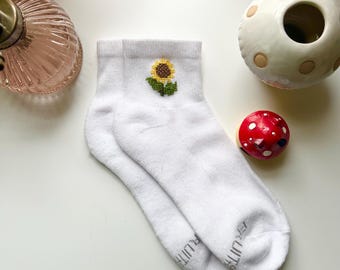 May include: White ankle socks with a small embroidered sunflower design in yellow, brown, and green.