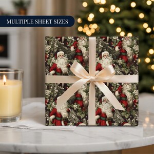 Puede incluir: Un regalo navideño envuelto con papel con un patrón de Papá Noel con traje rojo, rodeado de vegetación y bayas. Una cinta crema ata el paquete. A la izquierda del regalo hay una vela encendida.