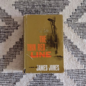 May include: A vintage paperback book titled "The Thin Red Line" by James Jones. The cover is a mustard yellow with the title in red and black text. The book has a worn appearance.