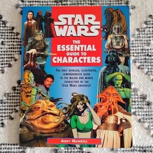 May include: A book titled "Star Wars: The Essential Guide to Characters" featuring various characters from the Star Wars universe. The cover is predominantly red and blue, with illustrations of characters like Darth Vader and Jabba the Hutt.