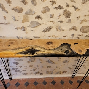 Peut inclure: Une console longue et étroite avec un plateau en bois naturel et un incrustation de résine époxy noire. La table a un design moderne avec des pieds en épingle à cheveux.