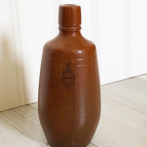 May include: A brown stoneware bottle with a rounded body and a narrow neck. The bottle has a raised circular design with the text "DATSON & CO. SUPERIOR" around the edge.