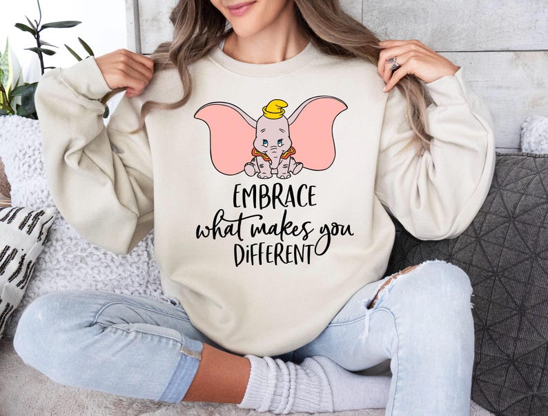 a woman sitting on a couch wearing a sweatshirt that says embrace what makes you different