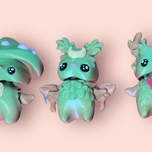 May include: Three small green and white figurines with cute faces. The figurines are shaped like a mushroom, a deer, and a creature with leaves on its head.