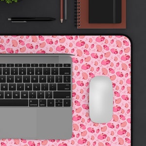 May include: A pink and white mouse pad with a repeating pattern of pink hearts. A laptop computer, a wireless mouse, and a pen are on the mouse pad.