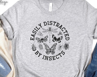 May include: Grey t-shirt with a black circle graphic that says "Easily Distracted by Insects" with a variety of insect illustrations. The shirt is labelled "Athletic Heather".