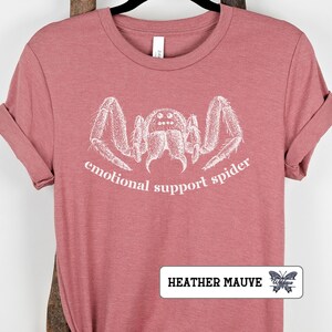 May include: Heather mauve t-shirt with a white graphic of a spider and the text "emotional support spider".