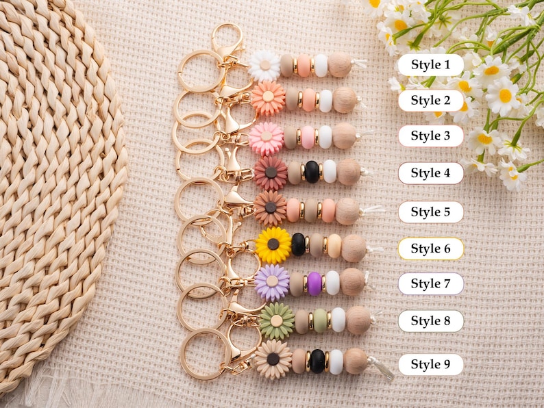 May include: A collection of nine keychains with gold-colored hardware. Each keychain features a variety of colorful silicone beads, wooden beads, and decorative flower accents. The text "Style 1" through "Style 9" is visible.