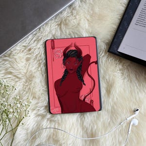 Può includere: Un dispositivo e-reader rettangolare che mostra un'illustrazione digitale di una figura demoniaca dalla pelle rossa con capelli scuri intrecciati, corna e una coda. Lo sfondo dell'opera è di un rosso solido con un sottile bordo rettangolare e cuori.