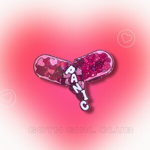 May include: A pink and red pill-shaped pin with the word "PANIC" written in white letters. The pill is broken open and filled with pink and red glitter hearts.