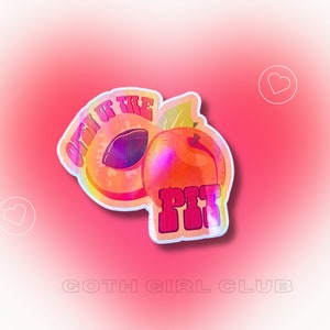 May include: A holographic sticker with two peach halves and the text "Open Up The Pit" in pink letters. The sticker is on a pink background with the text "Goth Girl Club" below it.