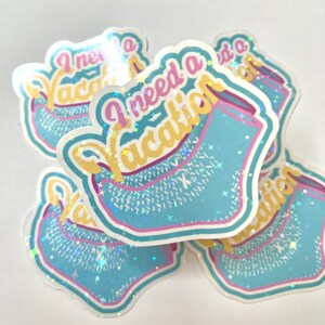 May include: Four iridescent blue and yellow stickers with the text "I need a vacation" in pink and yellow letters. The stickers have a glittery finish and a blue and yellow design that resembles a beach towel.