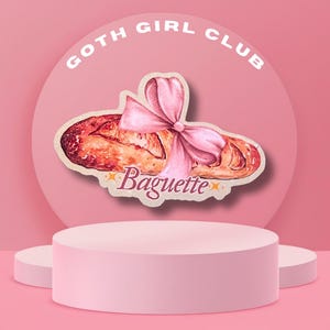Könnte beinhalten: Ein rosa Aufkleber mit einem Baguette, das mit einer rosa Schleife gebunden ist. Das Wort "Baguette" ist in einer Schreibschrift unter dem Brot geschrieben. Der Aufkleber befindet sich vor einem rosa Hintergrund mit den Worten "GOTH GIRL CLUB" in einem Halbkreis.