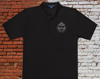 May include: Black polo shirt with a silver embroidered image of a heart with a cross and thorns on the left chest.