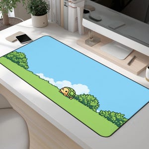 Puede incluir: Alfombrilla de escritorio rectangular con una tortuga de dibujos animados en una colina verde bajo un cielo azul con nubes blancas. La alfombrilla tiene un borde negro y está diseñada para su uso con un ordenador.