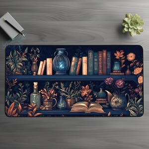 Puede incluir: Alfombrilla de ratón decorativa con una ilustración detallada de una estantería llena de libros, jarrones y plantas. La paleta de colores incluye tonos de azul, marrón y naranja, creando una estética vintage. El diseño incluye un libro abierto.