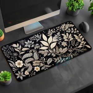 May include: Black mouse pad with a white floral design. The design features stylized leaves and flowers in a repeating pattern.