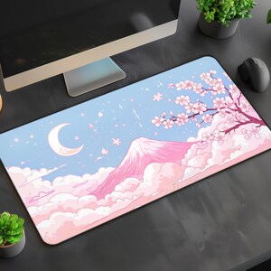 May include: A rectangular mouse mat with a Japanese landscape design. It features a pink mountain, cherry blossoms, a crescent moon, and a light blue sky. The mat is designed for use with a computer mouse.
