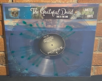 May include: A clear blue vinyl record with a green splatter design. The record is in a protective sleeve with the text "The Grateful Dead" and "This Is The End" printed on the front. The record is labeled "The Grateful Dead" and has a limited edition splatter vinyl label.
