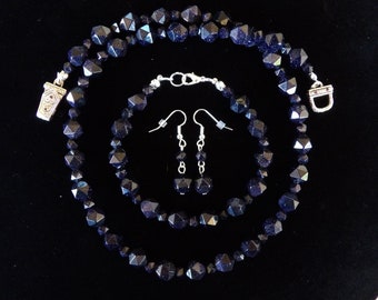 Puede incluir: Un conjunto de joyas de piedras preciosas azules en forma de estrella, que incluye un collar, una pulsera y pendientes. El collar y la pulsera tienen cierres plateados, y los pendientes tienen ganchos plateados.
