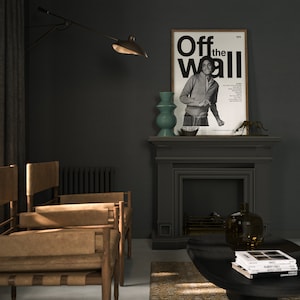 May include: A black and white poster with the text "Off the Wall 1979" and a photo of a man in a black and white striped shirt. The poster is hanging on a dark gray wall above a fireplace.