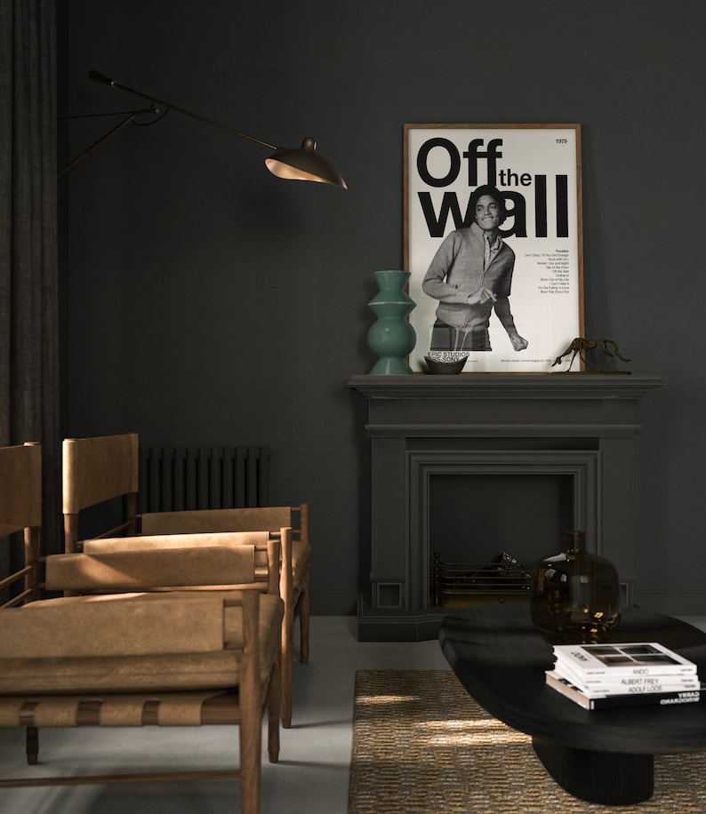 May include: A black and white poster with the text "Off the Wall 1979" and a photo of a man in a black and white striped shirt. The poster is hanging on a dark gray wall above a fireplace.