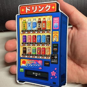 May include: A blue Japanese vending machine sticker featuring rows of colorful beverage bottles and cans, a top sign reading "Drink" in Japanese, a "Refresh" graphic with Mount Fuji, and various Japanese text labels for prices and machine functions.
