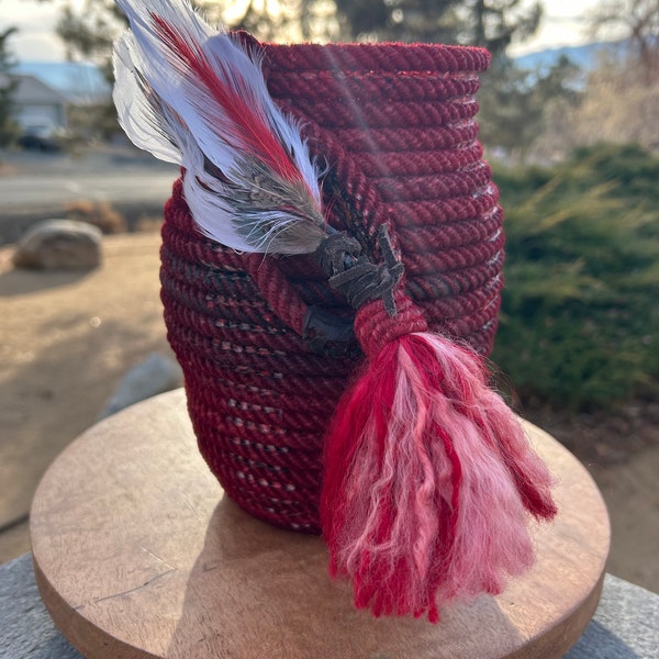 Lariat rope vase - custom dyed red.  Has feathers and tassle accent.  9” tall, and 5 1/4” across.