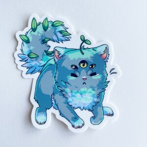 Puede incluir: Un gato azul y verde con tres ojos y una pequeña planta que crece en su cabeza. El gato tiene una cola esponjosa y mira hacia la derecha.