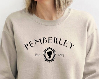 May include: A beige sweatshirt with a black graphic design that says "Pemberley Est. 1813" with a silhouette of a woman's head in a decorative frame.