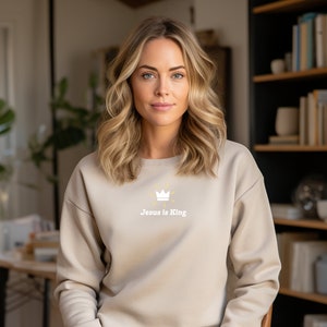 May include: A beige sweatshirt with a white crown and the text "Jesus is King" in yellow.