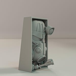 May include: A gray, futuristic gas mask with a cylindrical light and a handle, partially enclosed in a gray rectangular box. The mask has multiple circular and angular components, suggesting a protective or industrial design.